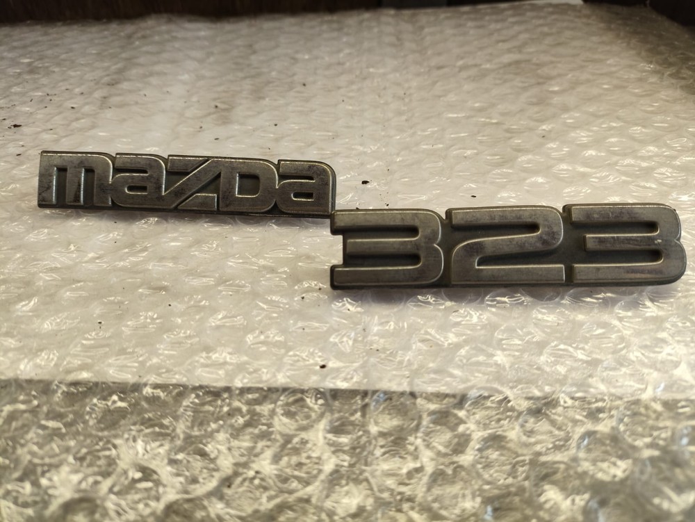 Эмблемы багажника Mazda 323